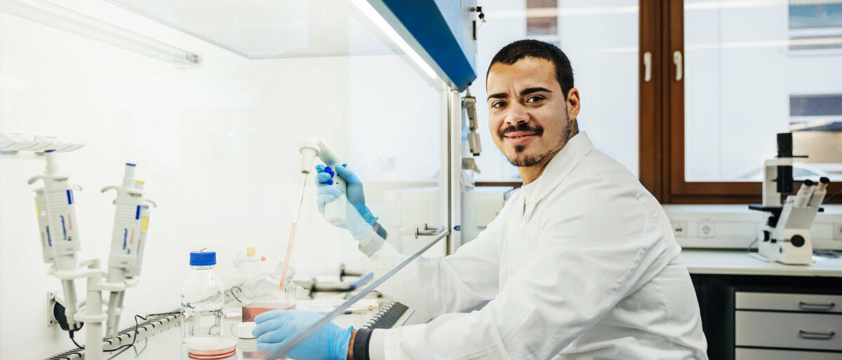 Ein junger Chemiker sitzt im Labor und führt gerade Tests durch © Hinterhaus Productions / Getty Images
