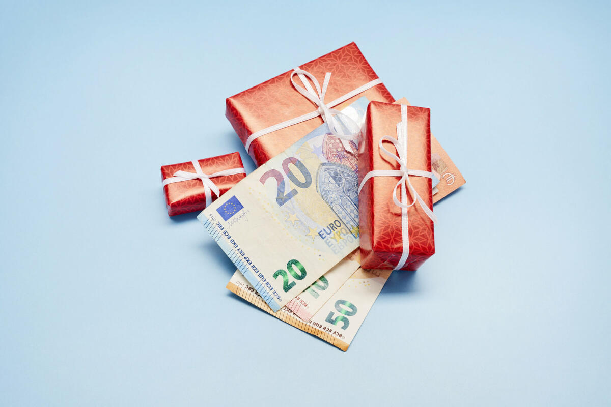 Rote Geschenke und Geldscheine auf blauem Untergrund ©  the_burtons / Getty Images