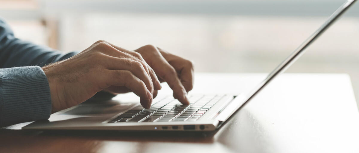 Die Hände eines Mannes tippen auf einer Laptoptastatur in der Nahaufnahme © Igor_kell / Getty Images