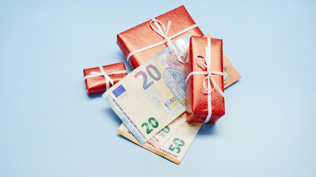 Rote Geschenke und Geldscheine auf blauem Untergrund ©  the_burtons / Getty Images