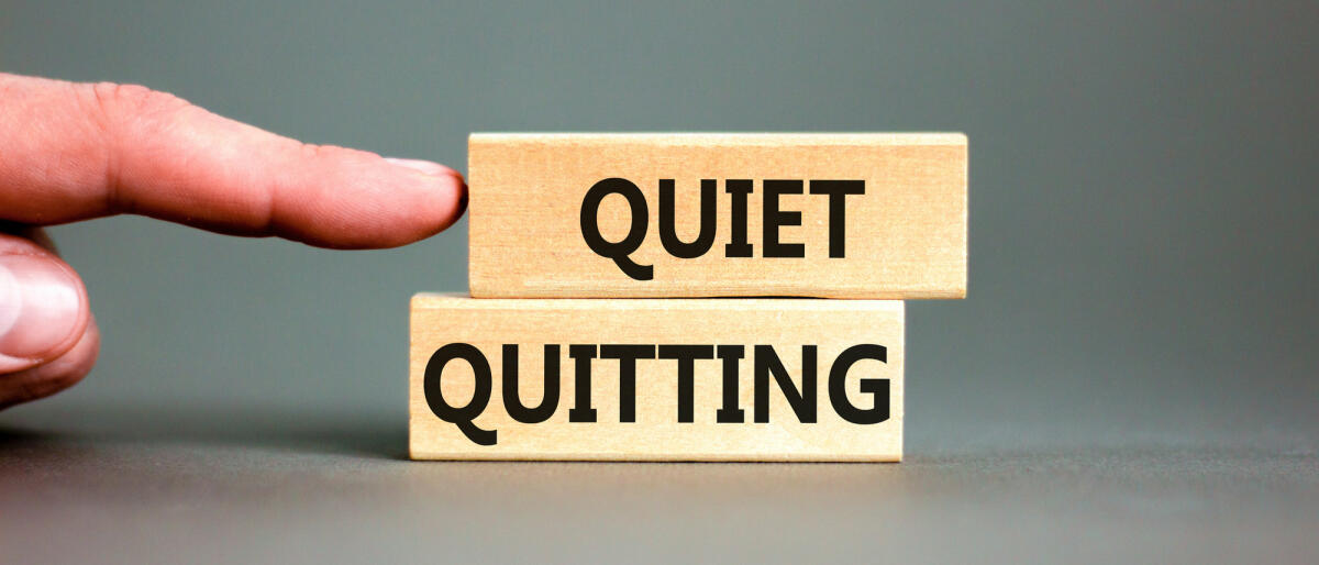 Quiet Quitting geschrieben auf zwei Holzblöcken auf einem grauen Schreibtisch vor grauem Hintergrund © Dzmitry Dzemidovich / Getty Images