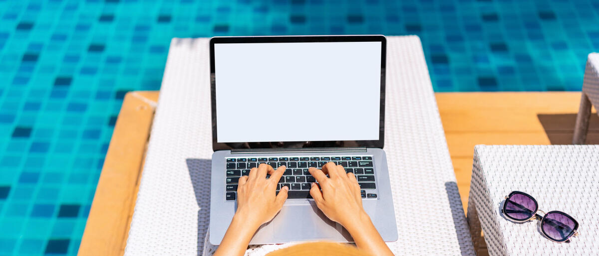 Junge freiberufliche Reisende arbeitet online mit Laptop während der Reise in den Sommerferien © kitzcorner / Getty Images
