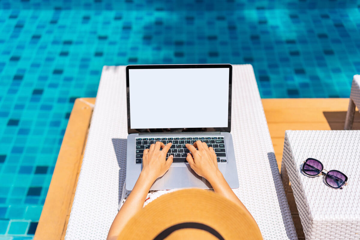 Junge freiberufliche Reisende arbeitet online mit Laptop während der Reise in den Sommerferien © kitzcorner / Getty Images