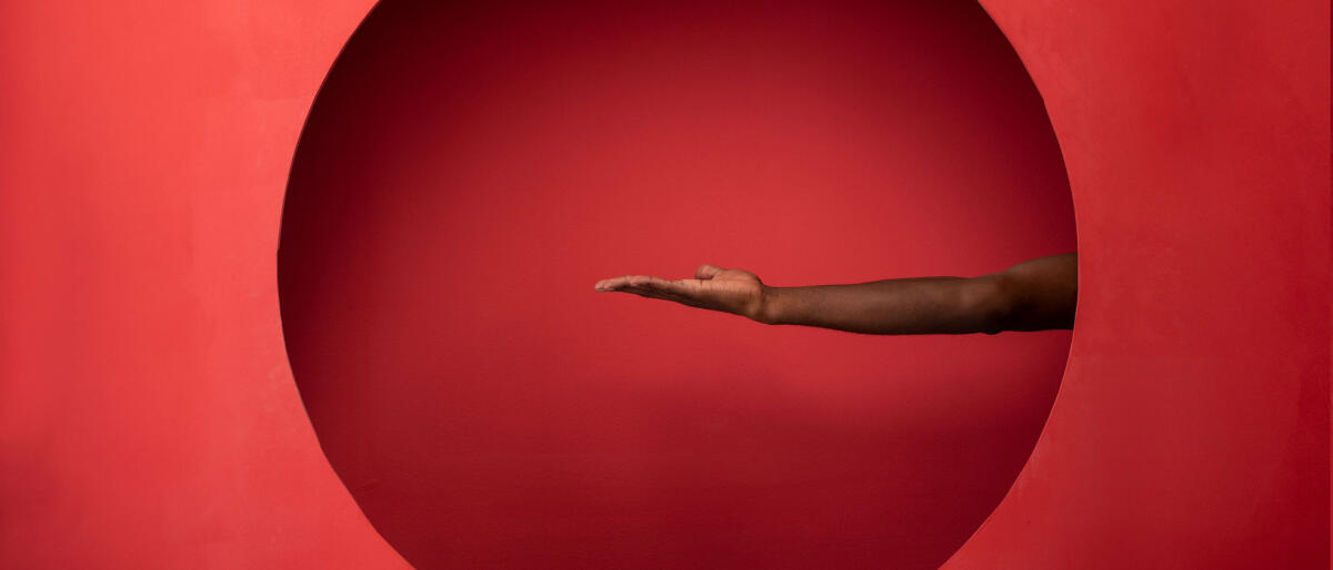 Arm und Hand auf rotem Hintergrund © artur carvalho / Getty Images