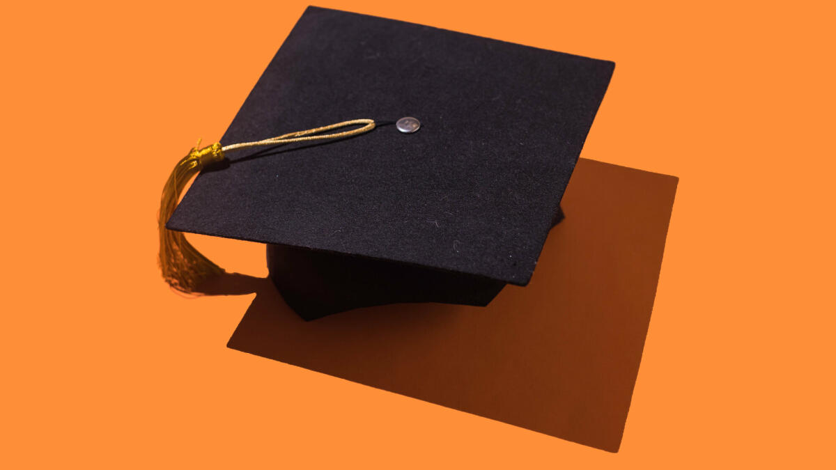 Schwarze Graduierungskappe mit goldener Quaste mit Schlagschatten auf orangem Hintergrund. © DBenitostock / Getty Images
