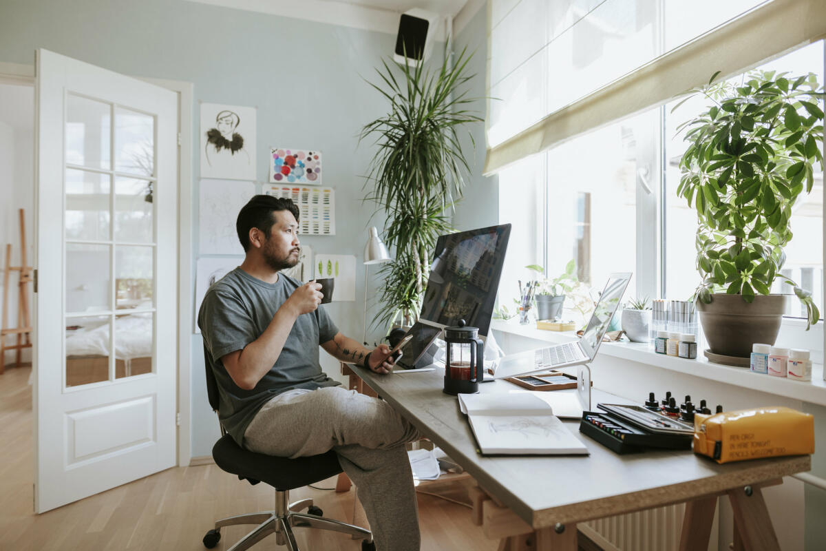 Mann mit Kaffee sitzt an Schreibtisch © visualspace / Getty Images