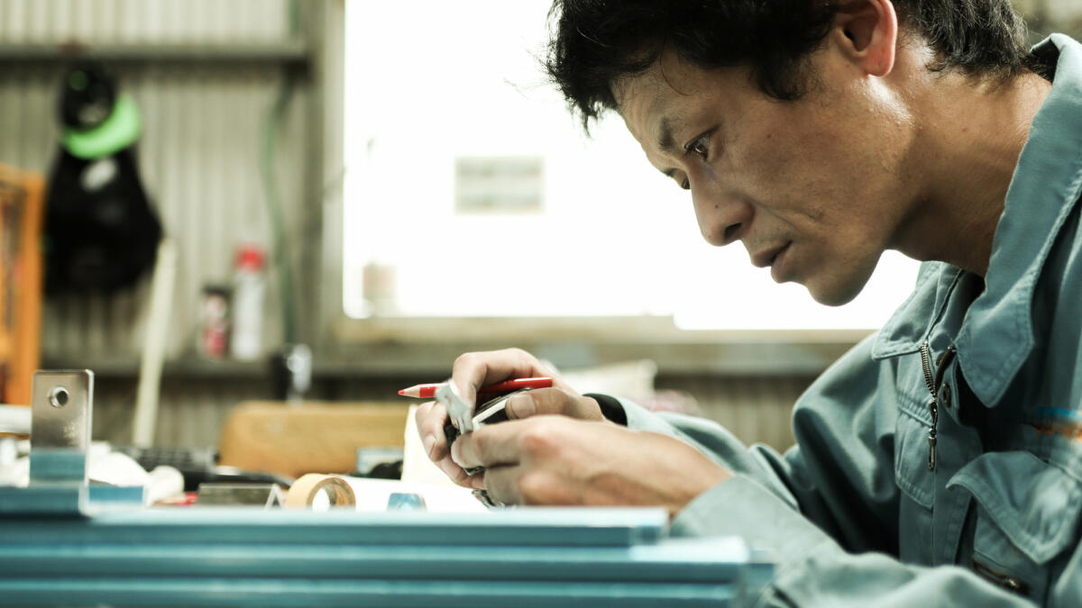 Werkstoffingenieur steht in der Fabrik und baut an einer Blaupause © kyotokushige / Getty Images