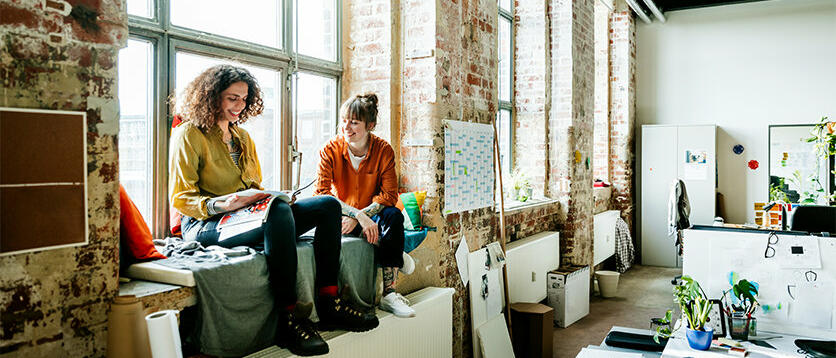 Zwei junge Frauen sitzen auf Fensterbank in Atelier © Hinterhaus Productions  / Getty Images