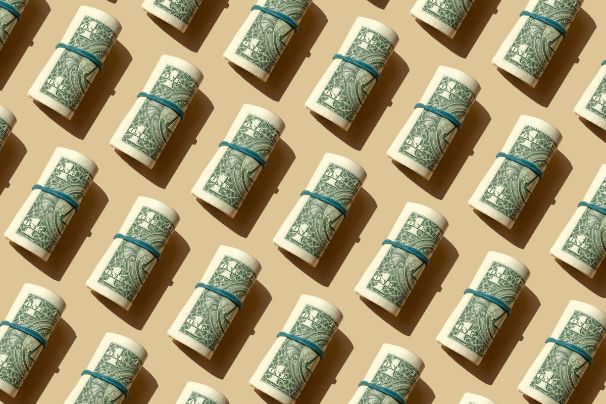 Rolle der amerikanischen Dollar-Banknoten auf dem beigen Hintergrund © Yulia Reznikov / Getty Images