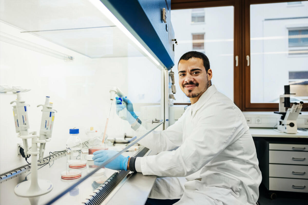 Ein junger Chemiker sitzt im Labor und führt gerade Tests durch © Hinterhaus Productions / Getty Images