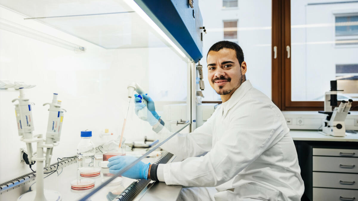 Ein junger Chemiker sitzt im Labor und führt gerade Tests durch © Hinterhaus Productions / Getty Images