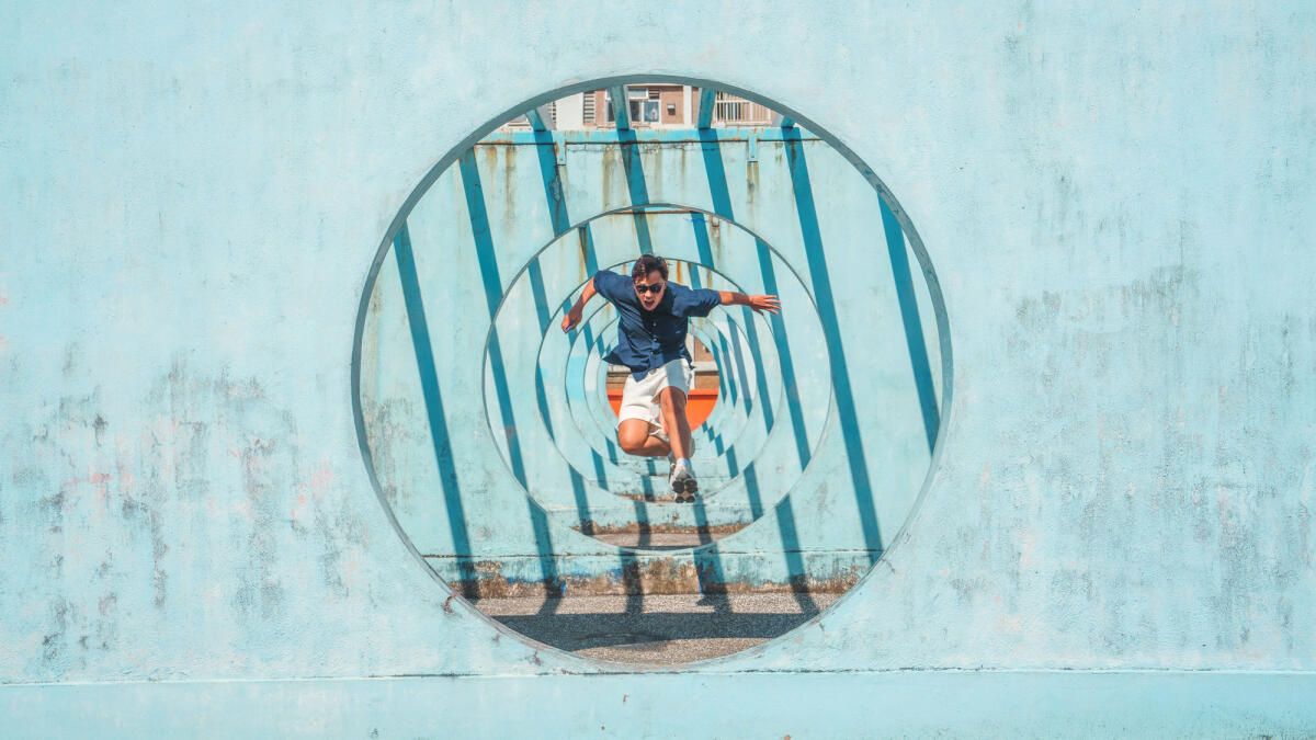 Asiatischer Mann, der aus dem Kreis springt Interessantes architektonisches Element © MR.Cole_Photographer / Getty Images
