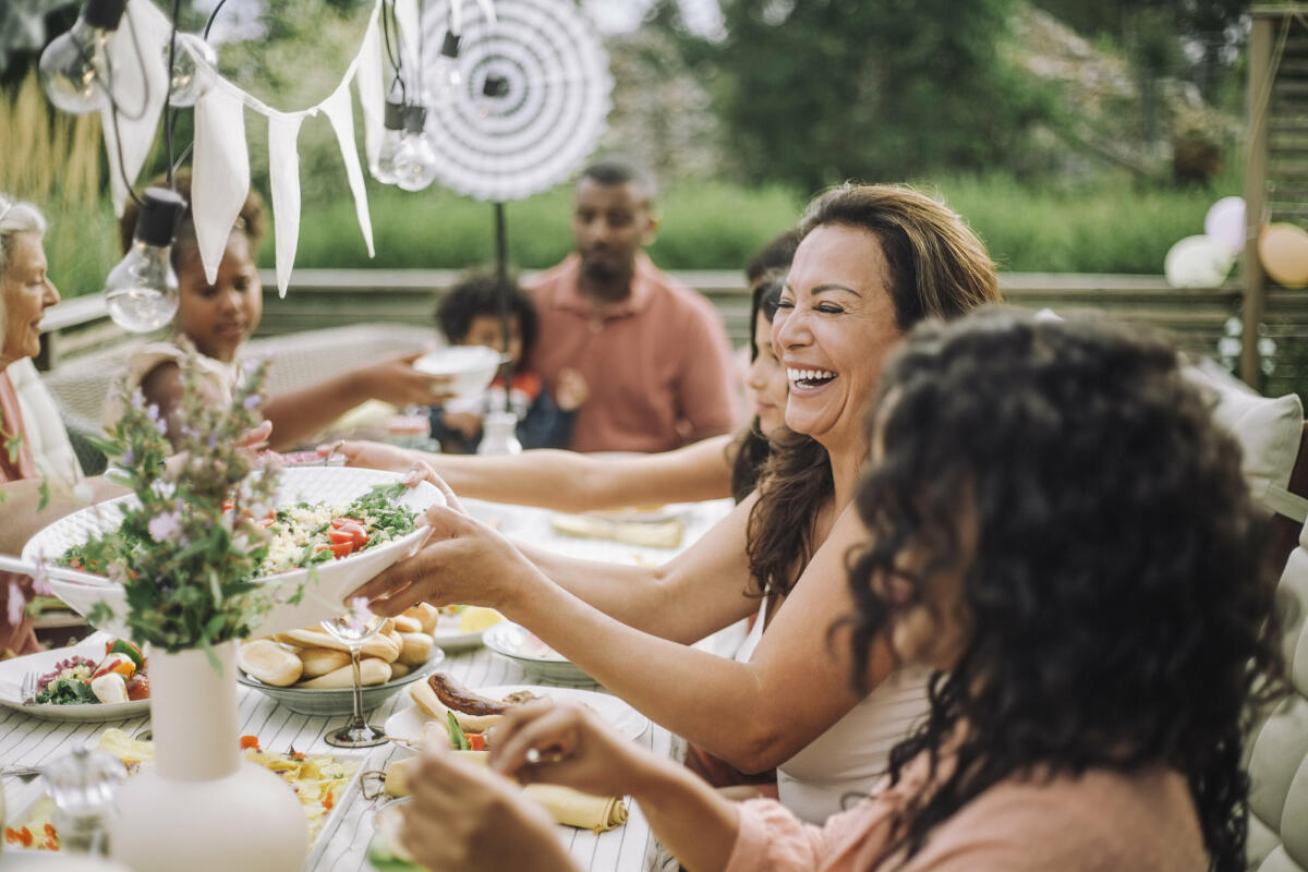 Menschen sitzen im Garten und essen zusammen © Maskot / Getty Images