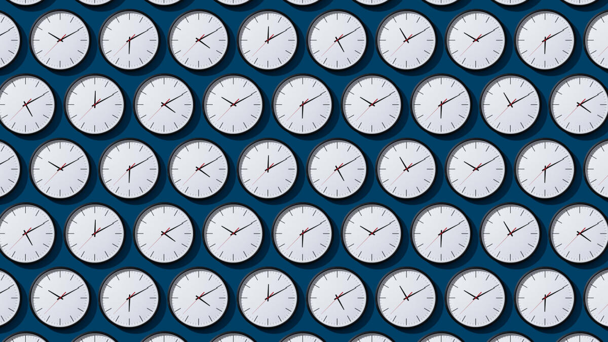 Ordentlich angeordnete Zeitzonen-Uhren auf festem blauem Hintergrund © MirageC / Getty Images