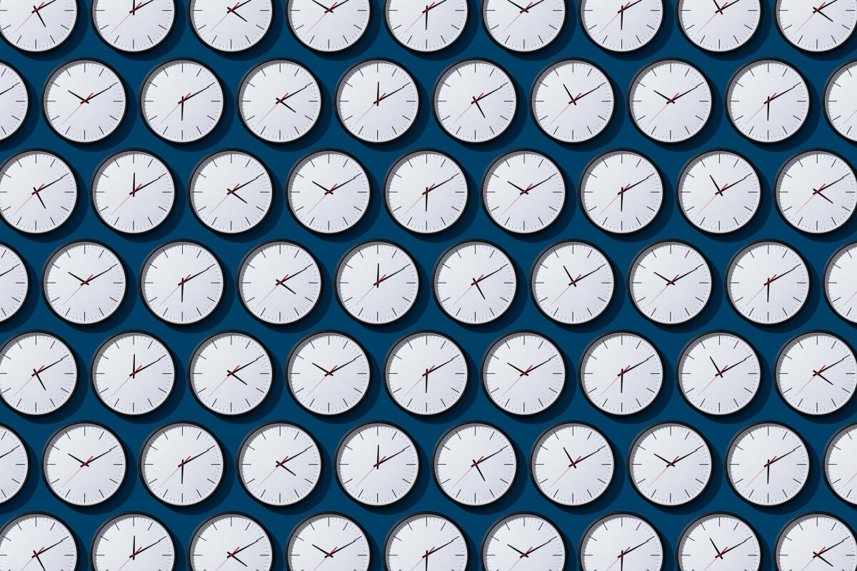 Ordentlich angeordnete Zeitzonen-Uhren auf festem blauem Hintergrund © MirageC / Getty Images