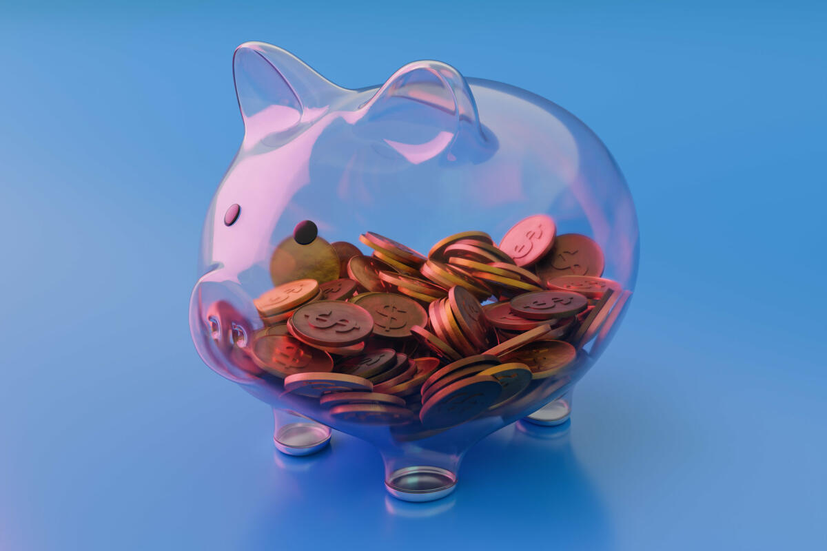 Sehen Sie durch transparentes Glas Sparschwein mit Münzen auf blauem Hintergrund © Constantine Johnny / Getty Images