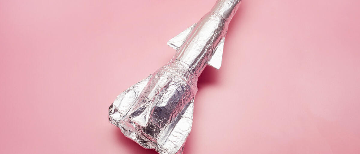 Stilleben einer selbstgebauten Rakete aus Aluminium auf rosa Hintergrund © the_burtons/Getty Images
