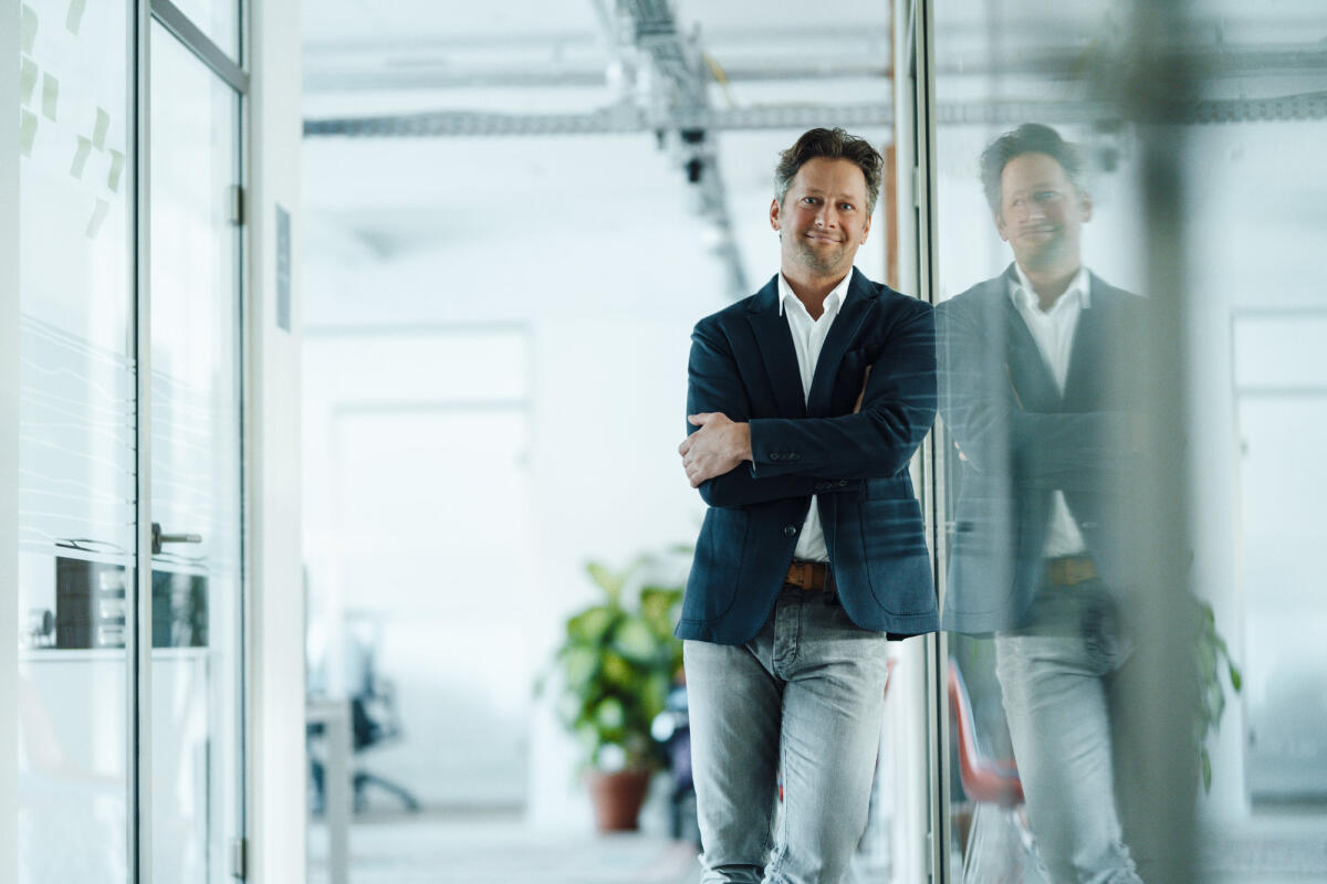 Mittelreifer Businessmann, der im Büro an einer Glasscheibe lehnt © Westend61 / Getty Images 