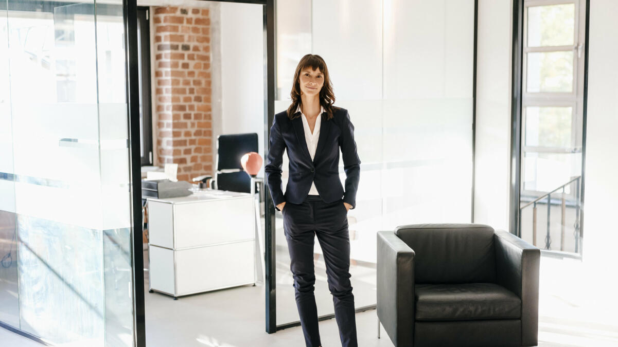 Erfolgreiche Geschäftsfrau im Büro stehend mit Händen in den Taschen © Westend61 / Getty Images