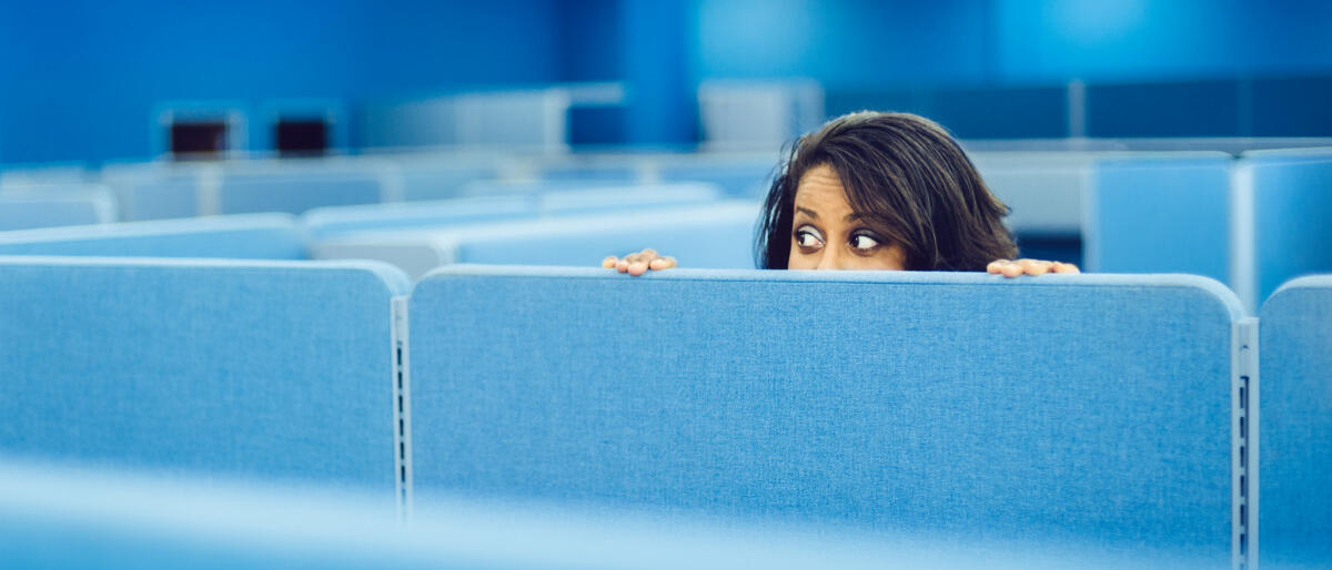Eine Frau versteckt sich bei der Arbeit. © Getty Images / ferrantraite