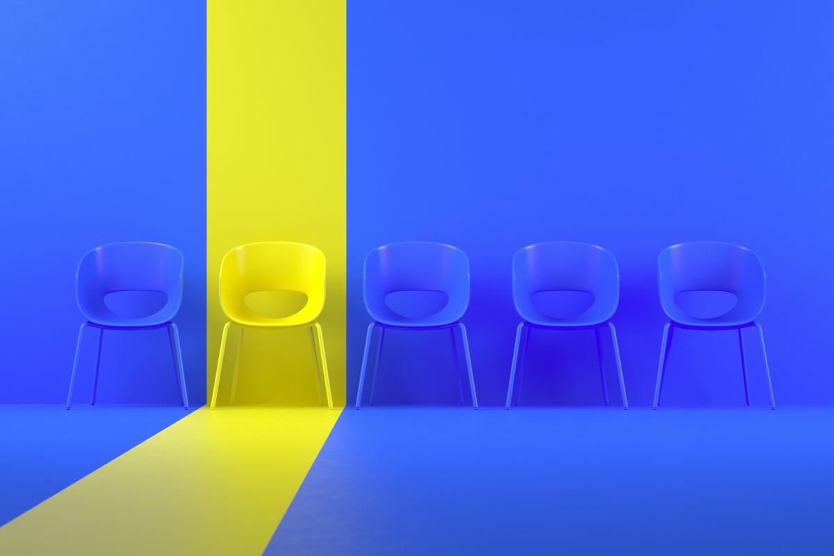 Blaue Stühle in einer Reihe und einen gelb hervorgehobenen © akinbostanci / Getty Images