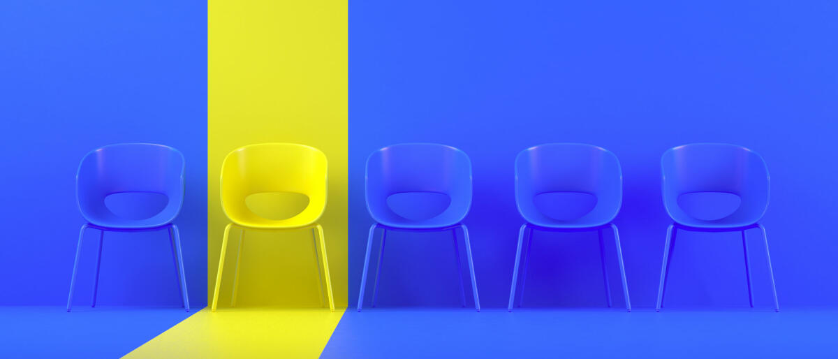Blaue Stühle in einer Reihe und einen gelb hervorgehobenen © akinbostanci / Getty Images