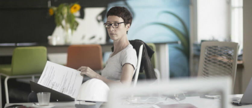 Frau sitzt am Schreibtisch und lies Dokumente © Sigrid Gombert / Getty Images