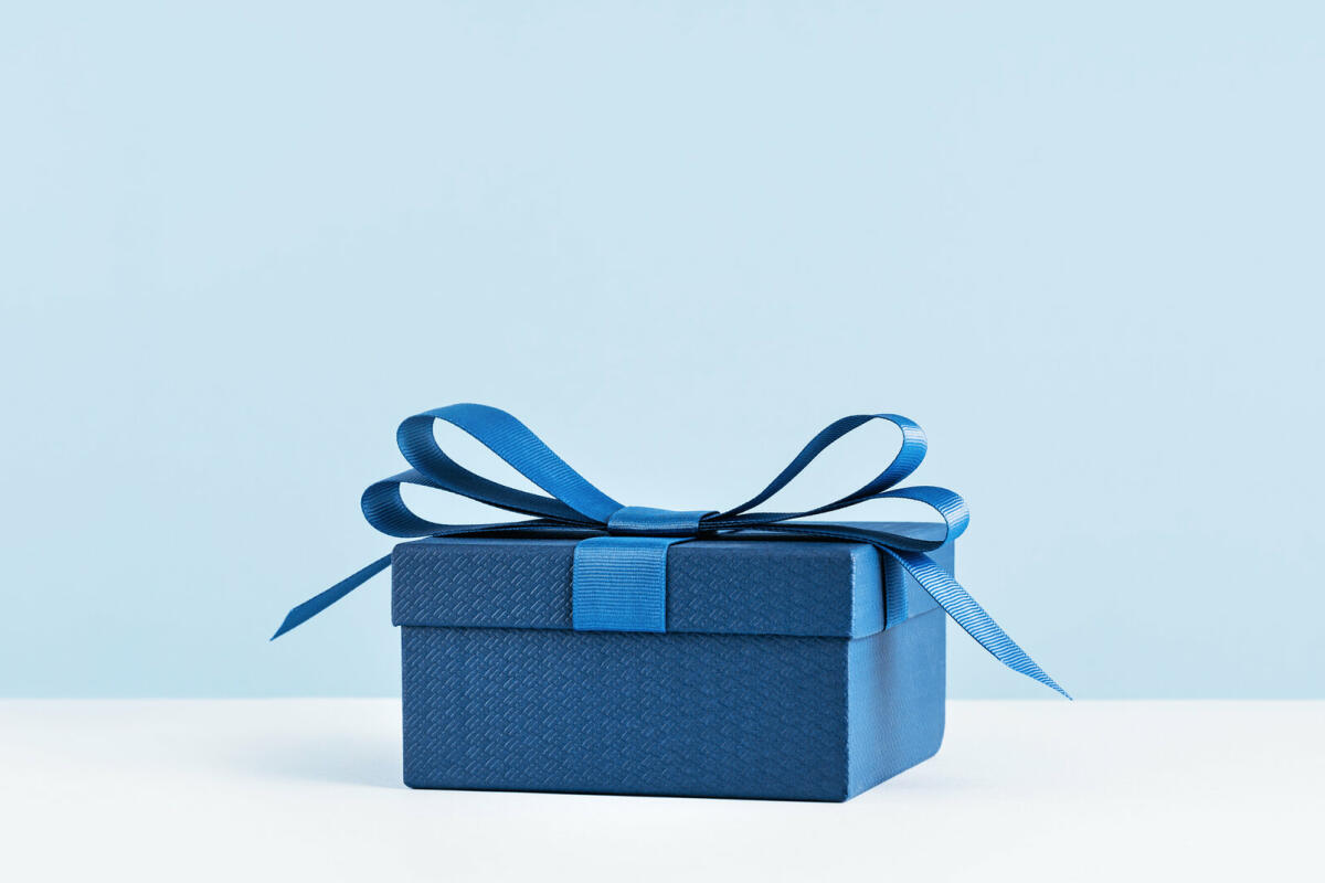 Eine Geschenkbox mit blauer Schleife auf hellblauem Monochrom © Tatiana Sviridova / Getty Images