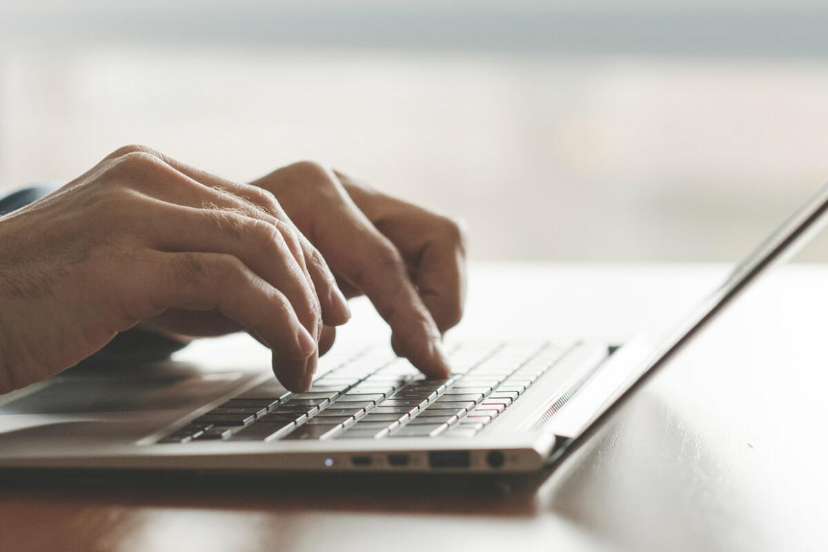 Mann tippt mit seinen Händen auf einem Laptop in der Nahaufnahme © igor_kell / Getty Images