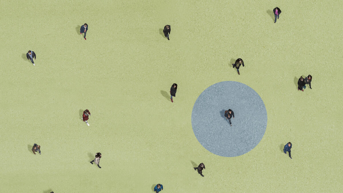 Gruppe von Menschen, die auf grünem Grund mit blauem Kreis gehen © Bernhard Lang / Getty Images