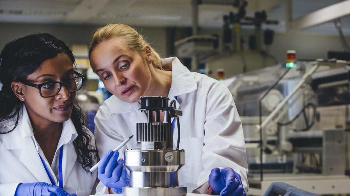Zwei Frauen stehen im Labor und prüfen gemeinsam ein technisches Gerät © SolStock / Getty Images