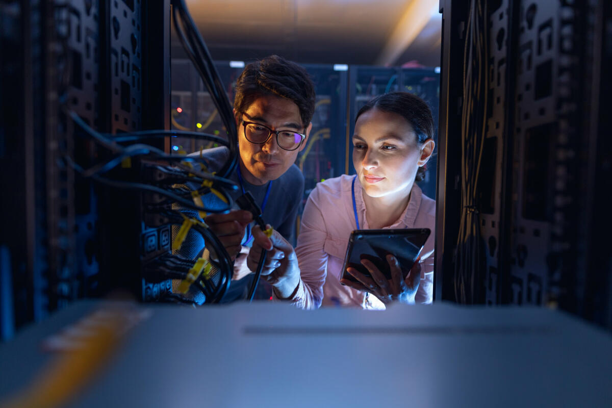 Diverse Ingenieure mit digitalem Tablet inspizieren den Server im Computer-Serverraum. Datenbankserver-Management- und Wartungskonzept. © Wavebreakmedia/ Getty Images