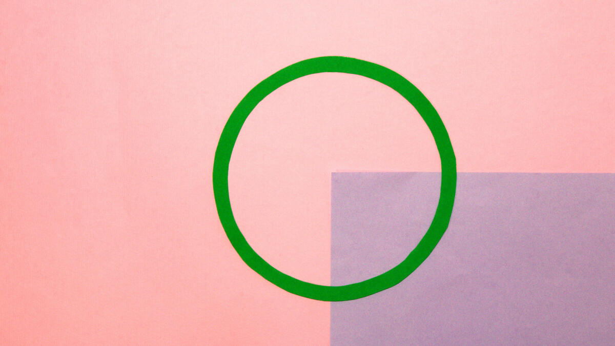 Rosa Hintergrund mit einem grünen Kreis in der Mitte als Kopierraum, ein Viertel des Hintergrunds ist lila © Isidora Jakovljevic / Getty Images