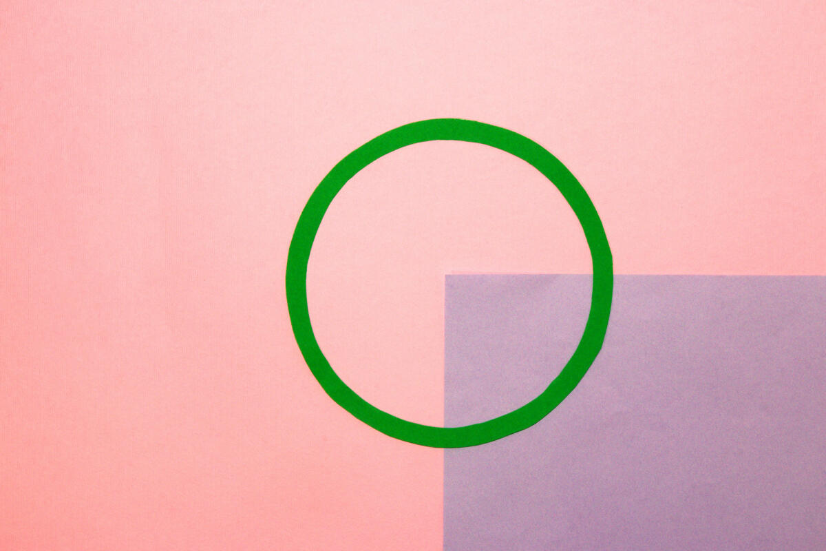 Rosa Hintergrund mit einem grünen Kreis in der Mitte als Kopierraum, ein Viertel des Hintergrunds ist lila © Isidora Jakovljevic / Getty Images