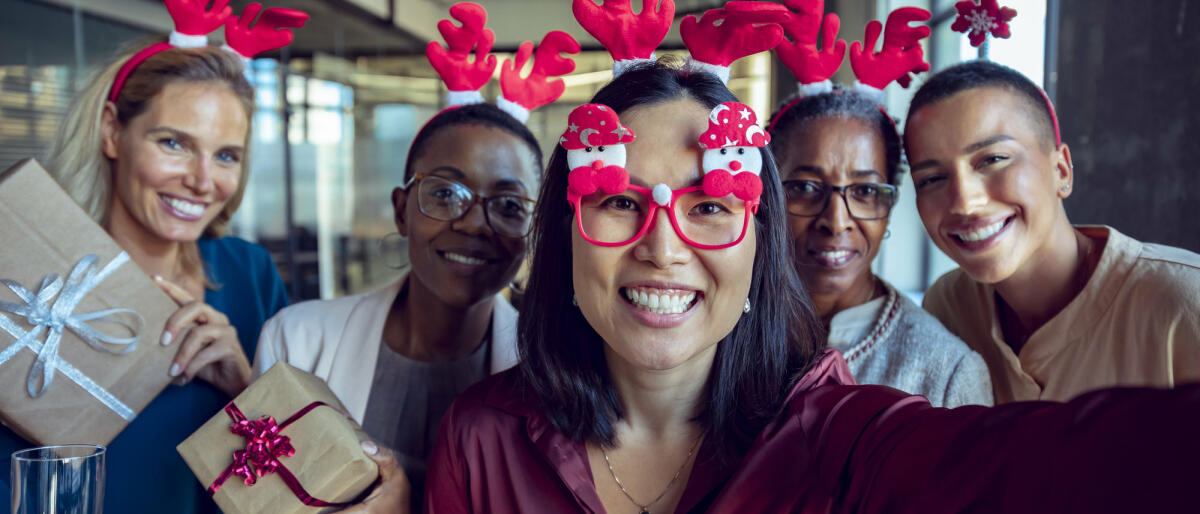 Kollegen mit Weihnachtsbrillen machen Selfie © Marko Geber / Getty Images