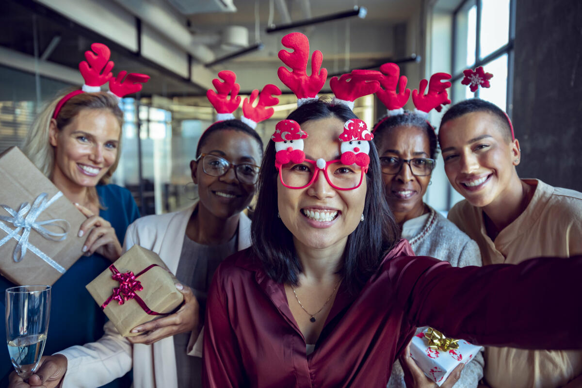 Kollegen mit Weihnachtsbrillen machen Selfie © Marko Geber / Getty Images