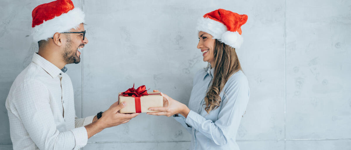 Geschäftsmann schenkt seiner Kollegin ein Geschenk. © VioletaStoimenova / Getty Images