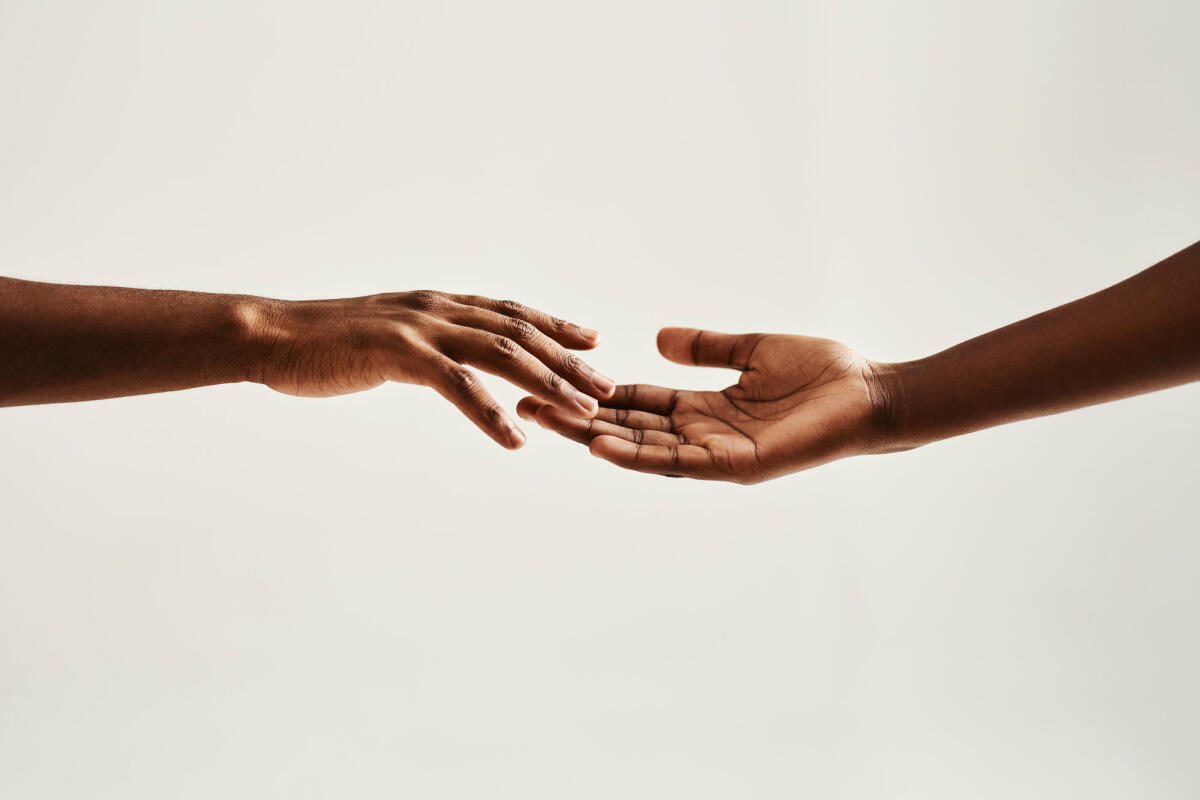Nahaufnahme von zwei unkenntlichen Menschen, die mit den Händen aufeinander zugreifen © Hiraman / Getty Images