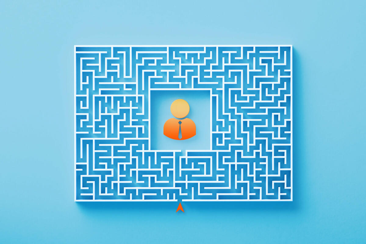 Orangefarbenes Geschäftsmannsymbol, das in der Mitte eines weißen Labyrinths auf blauem Hintergrund sitzt © MicroStockHub / Getty Images