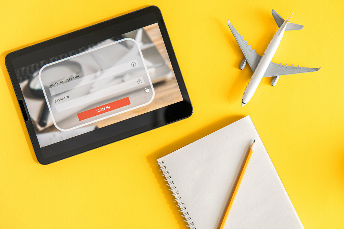 Login-Box, Eingabe von Benutzername und Passwort auf virtueller Digitalanzeige, Notebook und Flugzeug auf gelbem Hintergrund © puhimec / Getty Images