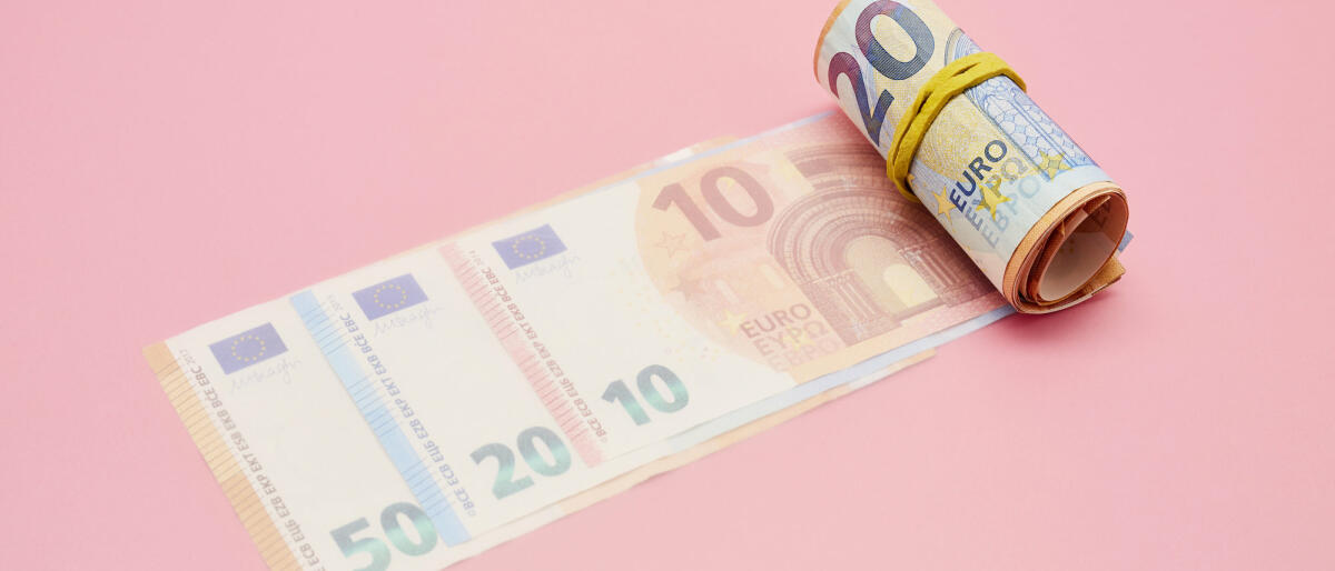 Eine Rolle von Euro Banknoten vor pinkem Hintergrund © the_burtons / Getty Images