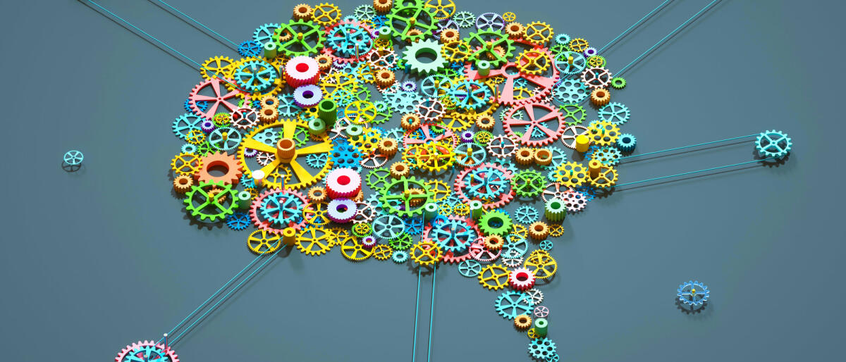Digital generated image of multi coloured gear wheels connected together in shape of brain on grey background. © Andriy Onufriyenko / getty images