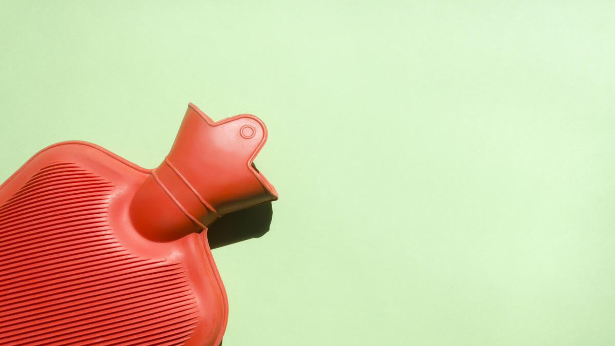 Rote Wärmflasche vor grünem Hintergrund © Elizabeth Fernandez / Getty Images