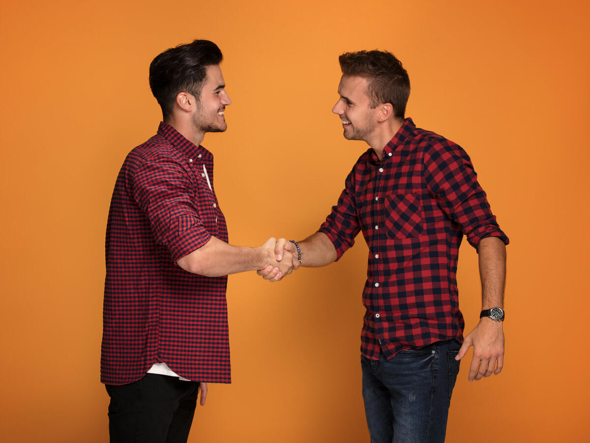 Zwei junge schöne Männer, Hände schütteln © NeonShot / Getty Images