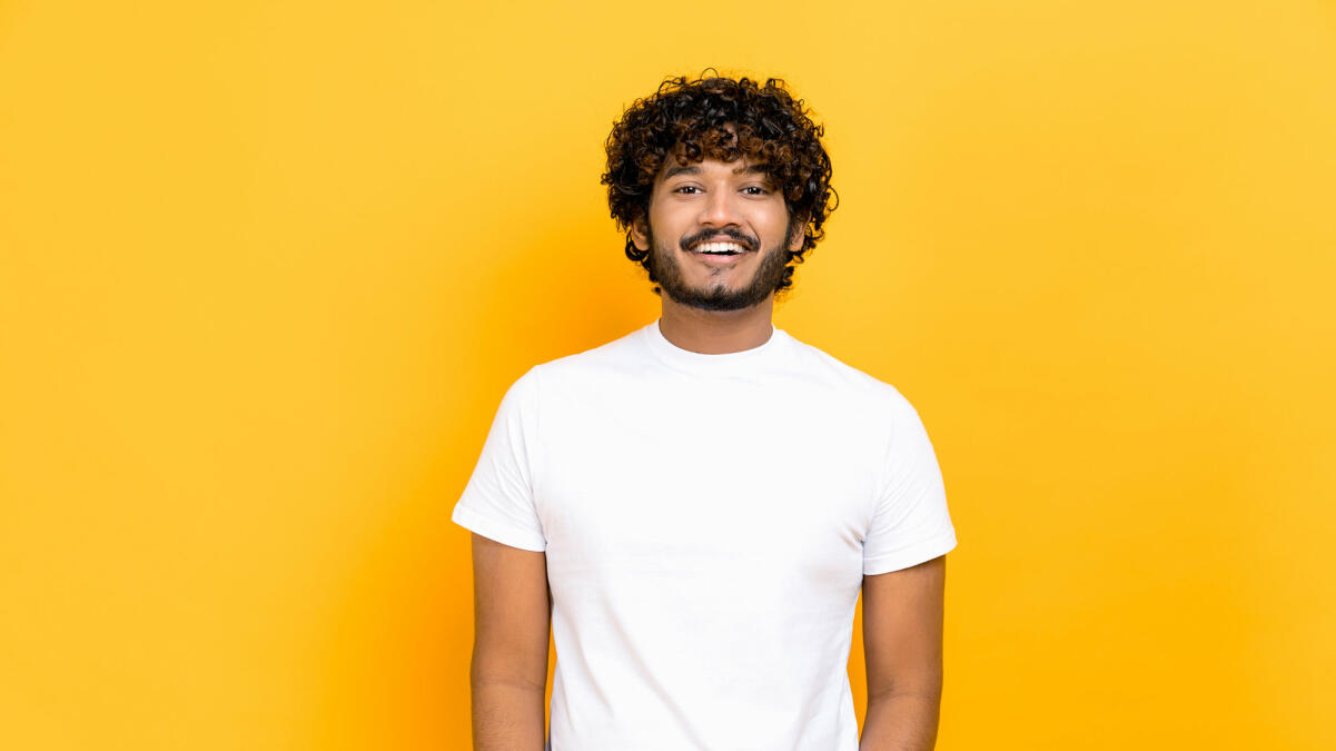 Porträt eines gutaussehenden, attraktiven, positiv lockigen indischen oder arabischen Mannes, der ein weißes Basic-T-Shirt trägt. © Kateryna Onyshchuk / Getty Images
