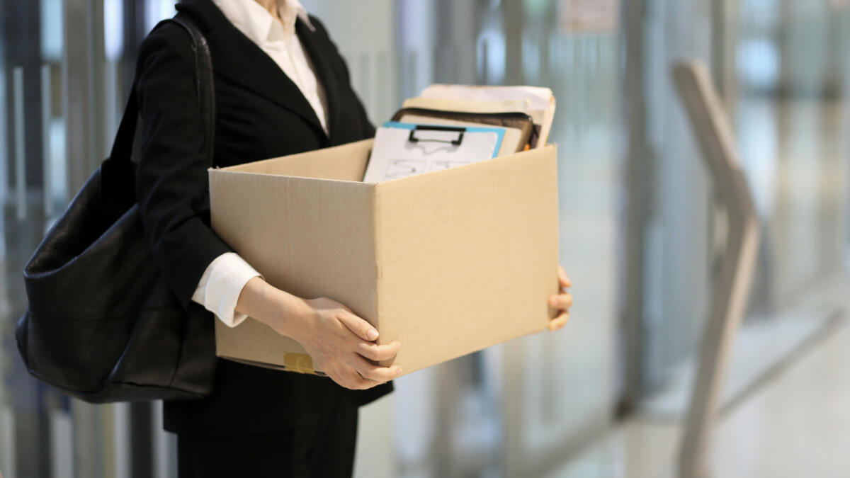 Frau hält Karton mit Bürosachen © RUNSTUDIO / Getty Images