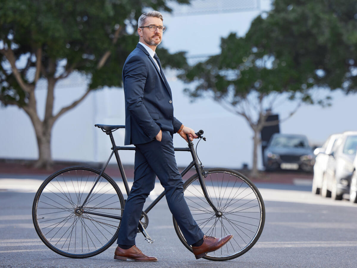 Aufnahme eines reifen Geschäftsmannes, der mit einem Fahrrad in der Stadt pendelt © PeopleImages / Getty Images