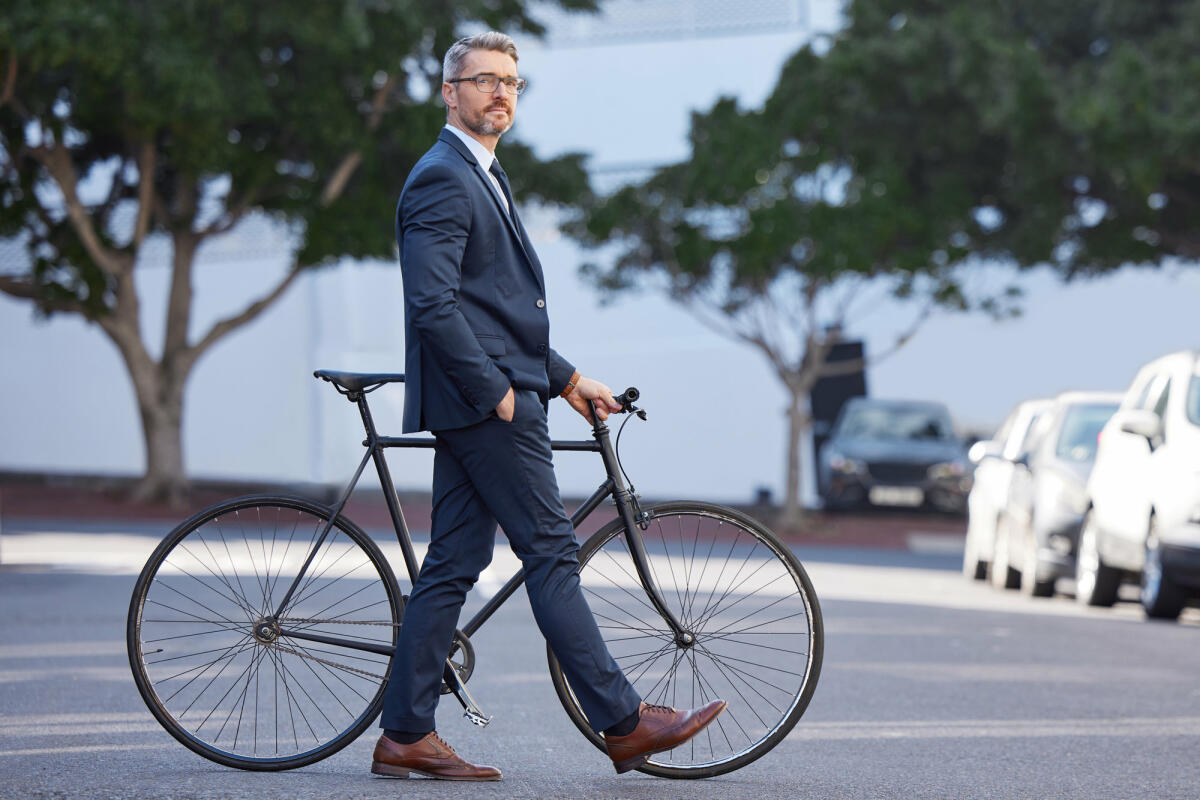 Aufnahme eines reifen Geschäftsmannes, der mit einem Fahrrad in der Stadt pendelt © PeopleImages / Getty Images