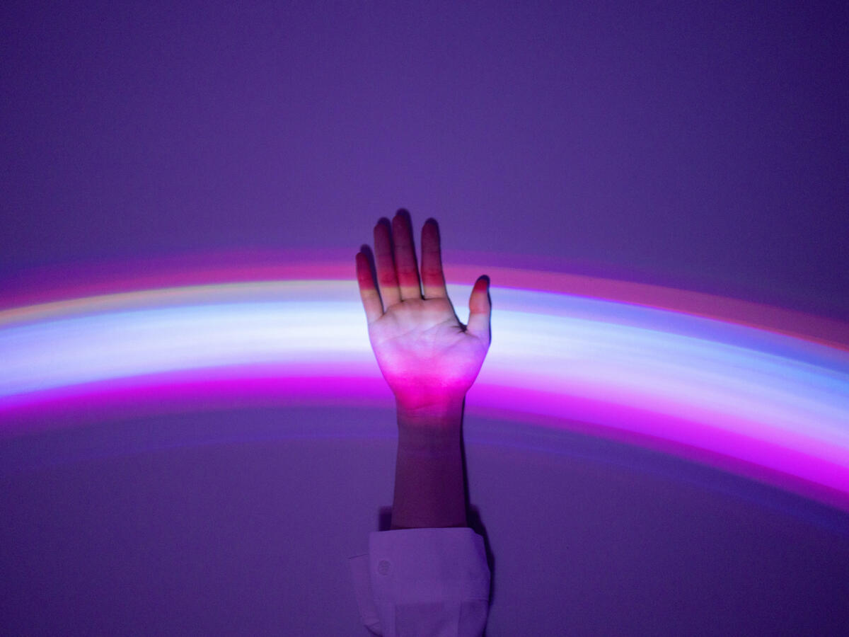 Hand, die sich meldet und in einem lila Lichtspiel aufleuchtet © Qi Yang / Getty Images